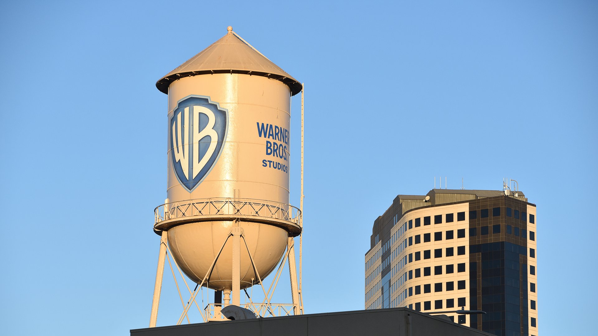 The Warner Bros. Studios water tower rising above a rooftop in Burbank, California, lit by warm evening light